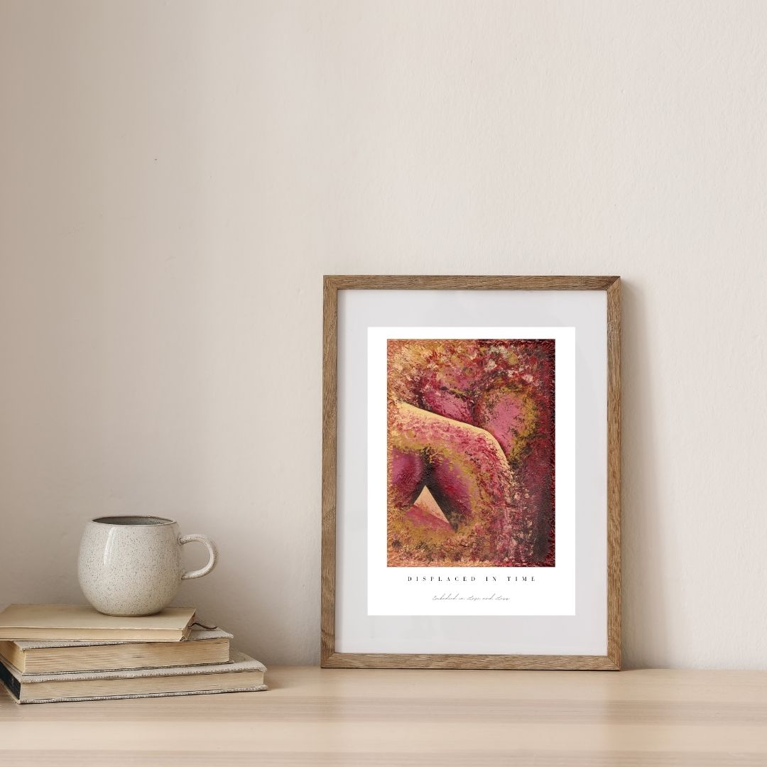 Framed artwork on a wall with books and a mug below