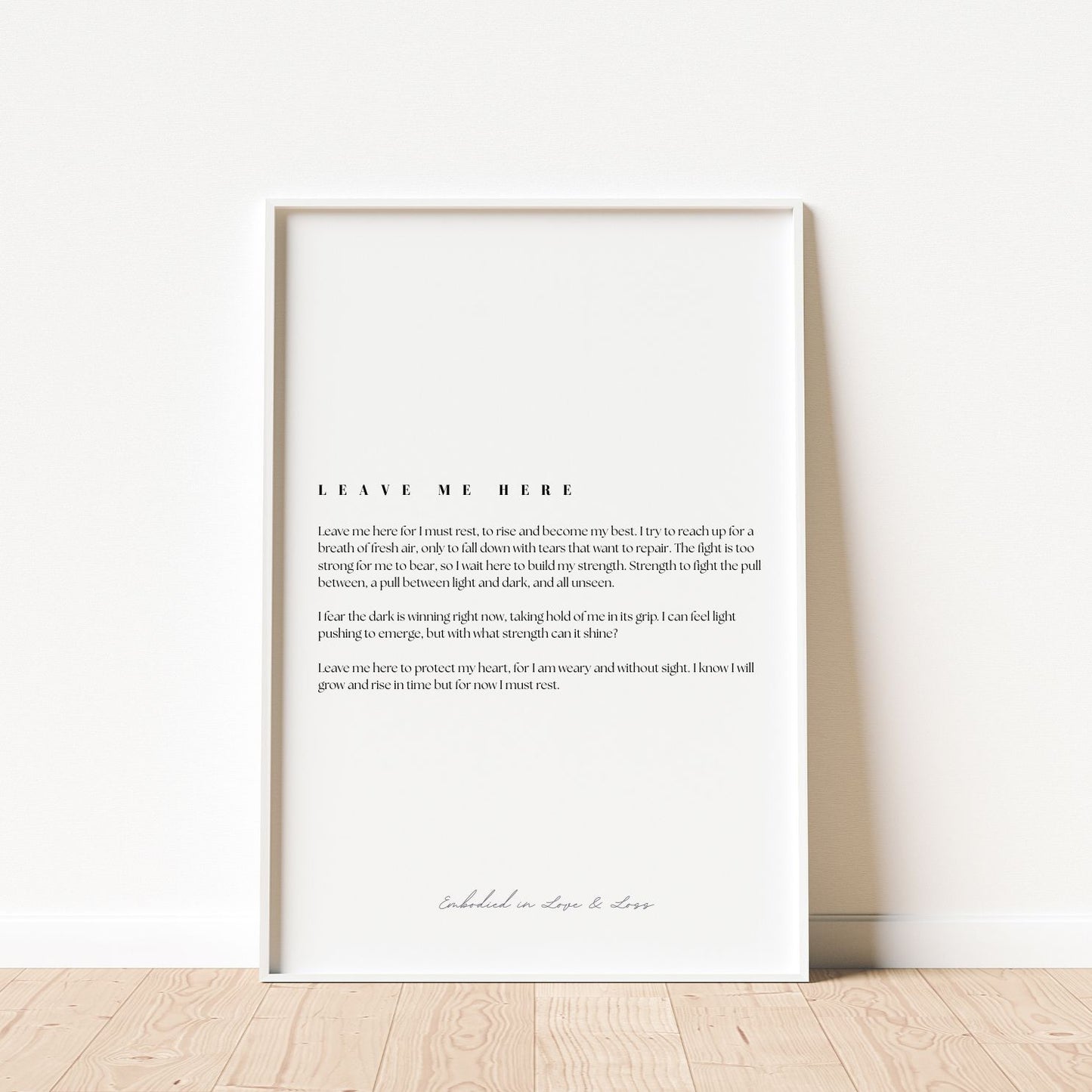 Framed text art print on a white wall with wooden floor