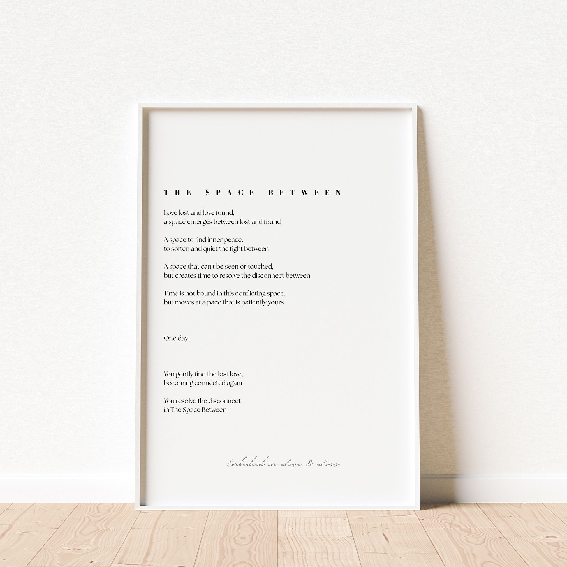 Framed poem titled 'The Space Between' on a white wall.