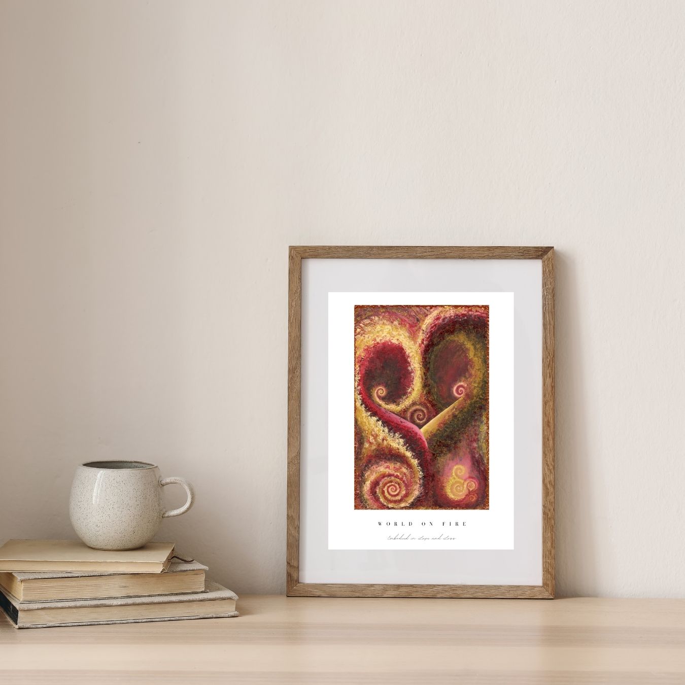 Framed abstract art print on a wall with books and a mug below