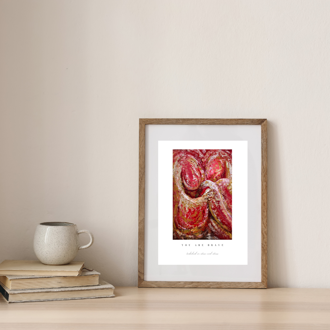 Framed artwork on a wall with books and a mug below