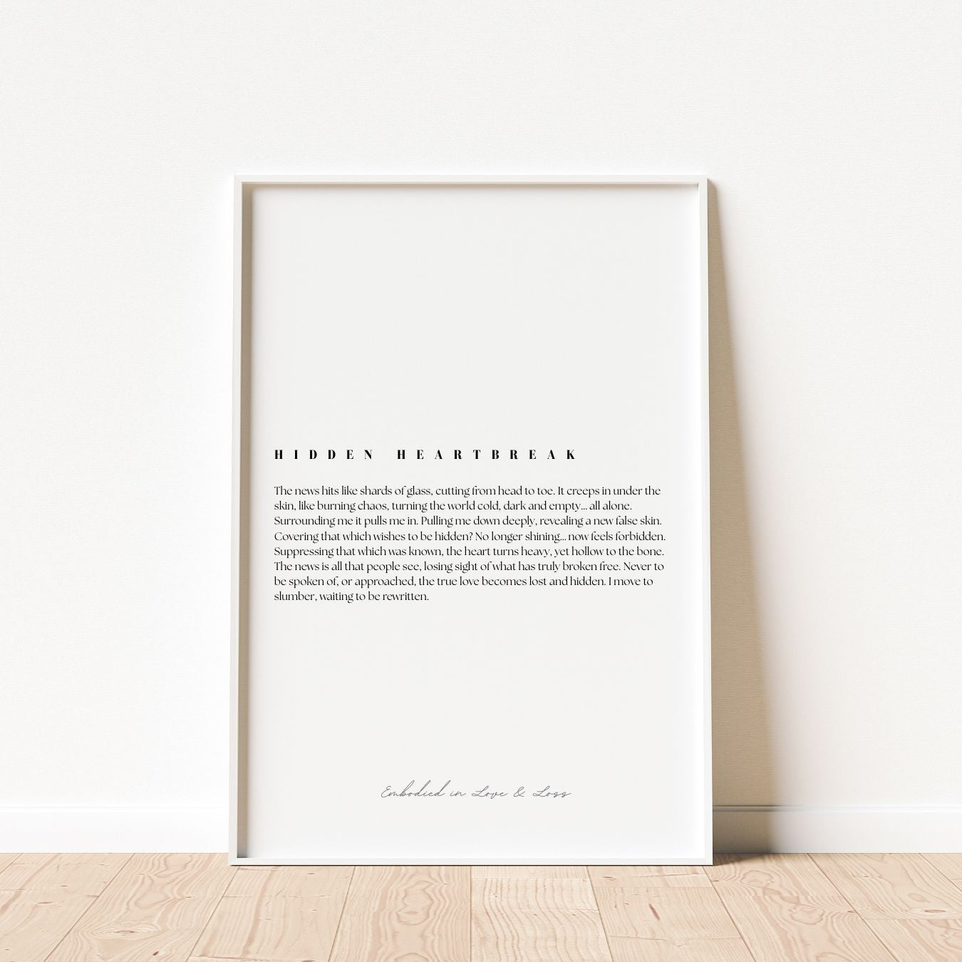 Framed text art on a white wall with wooden floor
