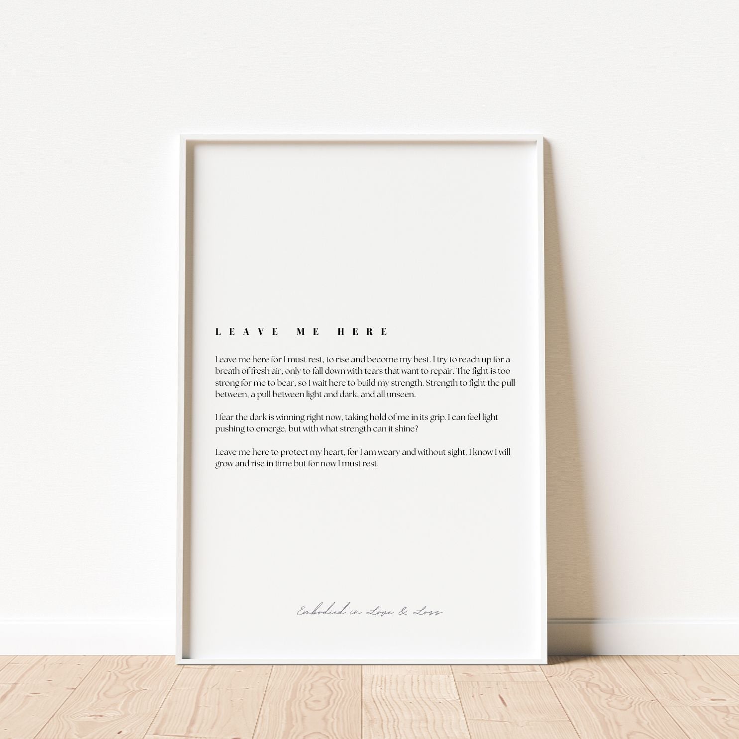 Framed text art print on a white wall with wooden floor