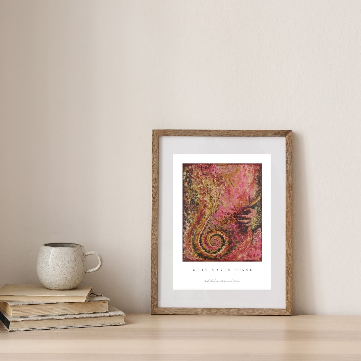 Framed abstract art print on a wall with books and a mug below